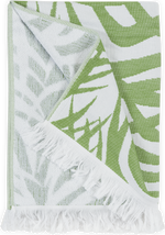 The Matouk Zebra Palm Beach Towel, Jungle features a green and white tropical leaves design, cotton terry texture, and white fringe edges.