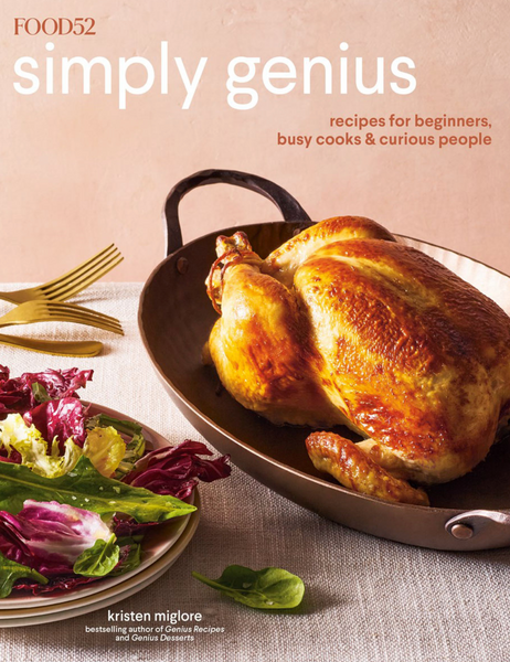 A roasted chicken in a pan, accompanied by a side salad, featured on the cover of Common Ground's Food52 Simply Genius cookbook.
