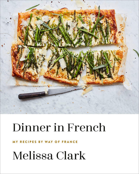 Puff pastry tart with asparagus topping displayed with a knife on a kitchen counter, advertising French cooking in a cookbook titled "Common Ground" by Melissa Clark.