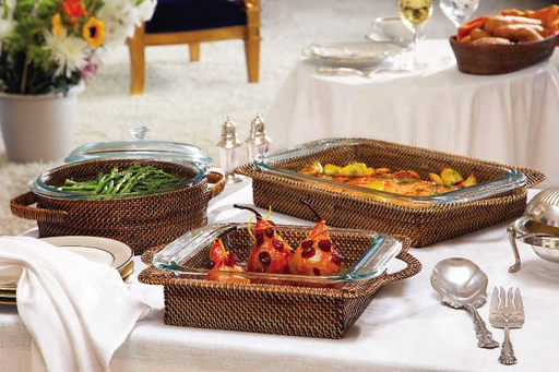 A dining table set with Calaisio's Rectangular Baker with Pyrex Insert—artisan-made—serving green beans, roasted veggies, and stuffed apples, surrounded by plates, utensils, bread, and water-vine accents for rustic charm.