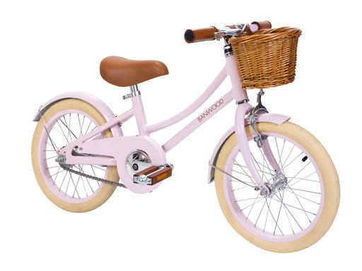 A pink Banwood Classic Children’s Bicycle with a wicker basket has a retro feel.