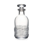 The Echo Lake Decanter by Simon Pearce features textured horizontal lines and a round stopper, expertly crafted by master glassblowers. Shown here in clear glass against a white background.
