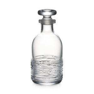 The Echo Lake Decanter by Simon Pearce features textured horizontal lines and a round stopper, expertly crafted by master glassblowers. Shown here in clear glass against a white background.