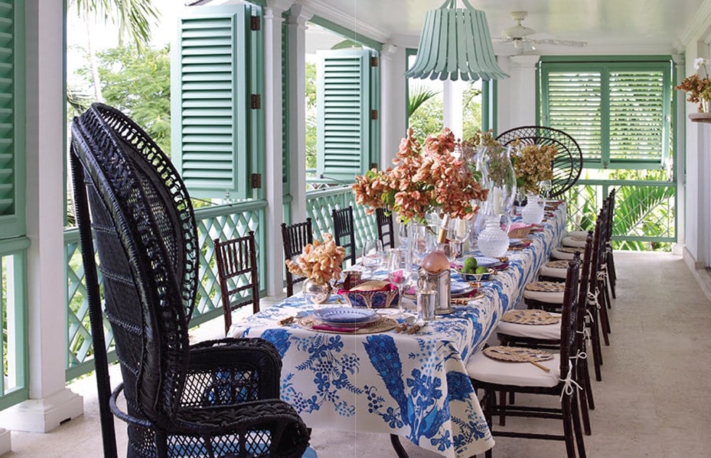 A table set on a porch with green shutters inspired by island living and Common Ground's Island Hopping interiors.