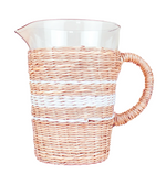 The Be Home Seagrass White Stripe Pitcher features a clear glass body wrapped in beige and white seagrass, a sturdy handle, and a convenient pour spout for easy serving.