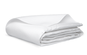 A neatly folded Alba Bedding Collection blanket or towel in white by Matouk, crafted from Egyptian cotton sateen and OEKO-TEX® Standard 100 certified, is placed on a flat surface.