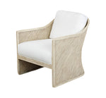 The Almario Lounge Chair by PALECEK is a beige upholstered lounge chair with a rattan frame, curved armrests, and plush white cushions, beautifully set against a pristine white background.