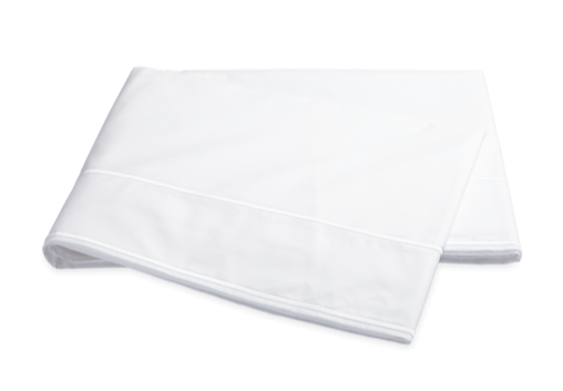 A Matouk Ansonia white cotton percale sheet draped over a black background, exuding luxury.