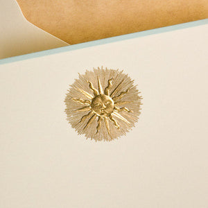 The Sunburst Card Set by Printery features cream ecru cards with a gold sunburst face design, each partially inside a tan envelope.