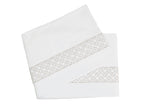Two plush white folded towels, crafted from luxurious Egyptian cotton with a gray geometric pattern along the edges, rest against a pristine white background. These exquisite towels perfectly complement any piece from the HIVE Exclusive Rovella Bedding Collection by Matouk in Camel.