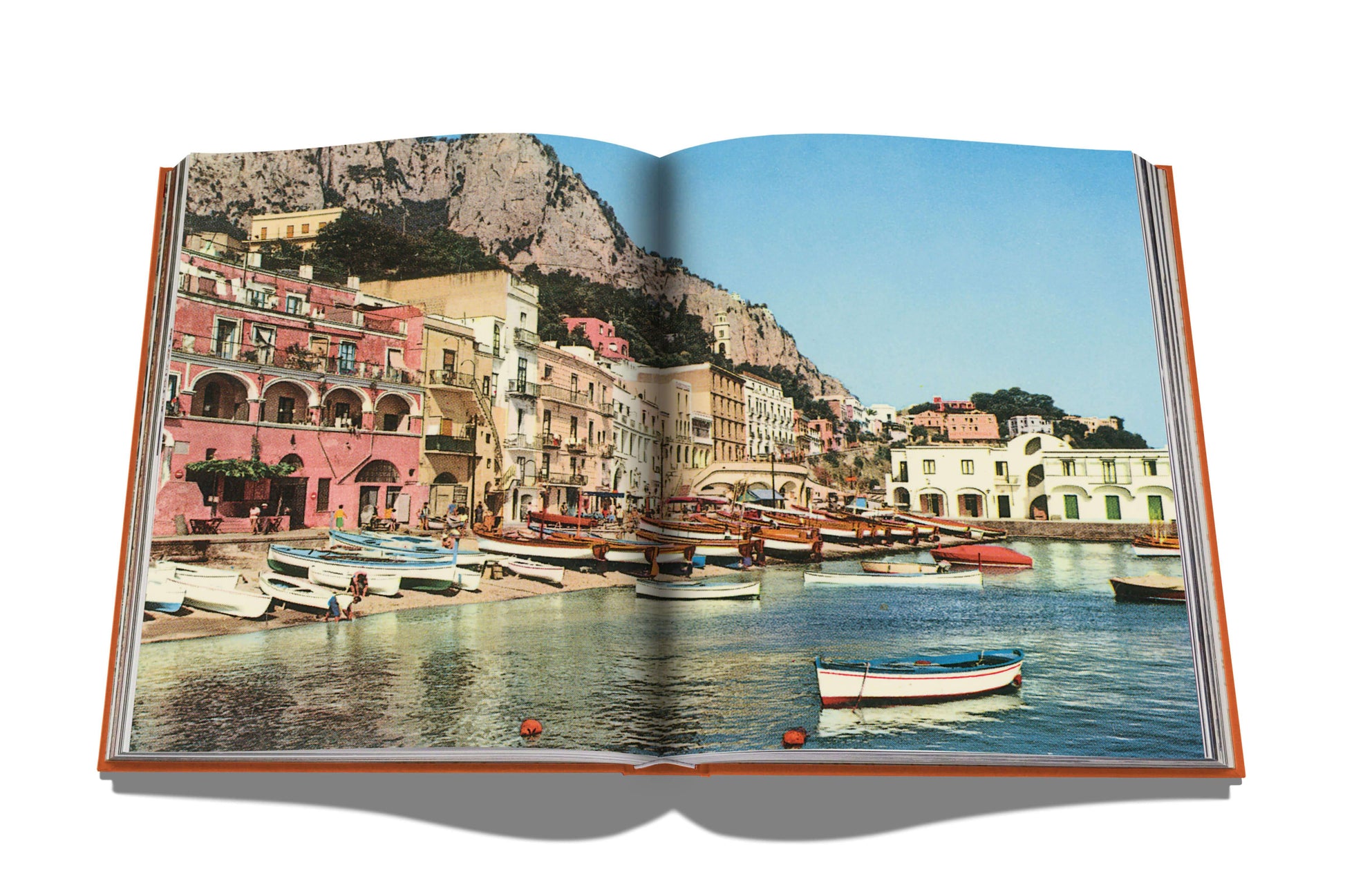 Open travel book featuring a colorful coastal village with Capri Dolce Vita boats and cliffs, embodying the Mediterranean spirit by Assouline.