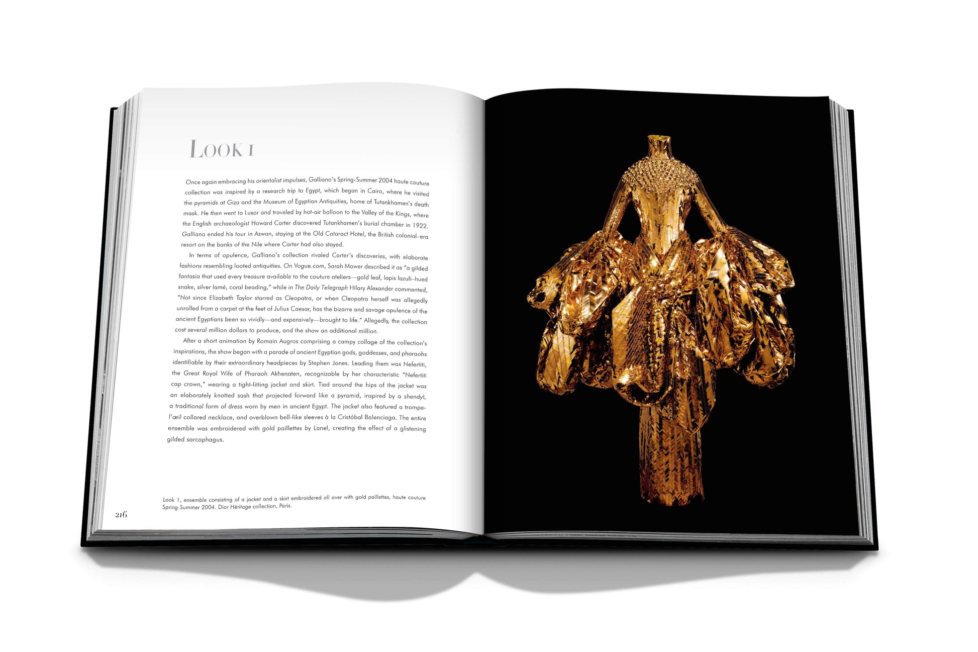 Open book displaying a text page on the left and an image of an elaborate, gilded garment by John Galliano on the right. The haute couture piece appears opulent and intricately designed, taking up the full right page in Dior V by Galliano by Assouline.