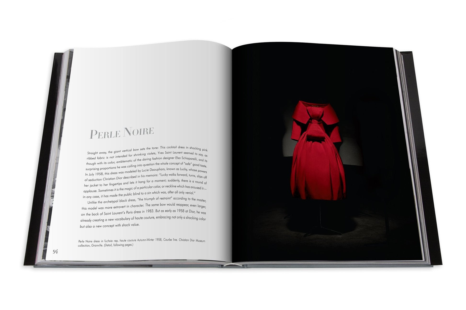 An open book displays a page of text on the left and a photo of a red dress on a black mannequin against a dark background on the right. The title on the left page reads "Dior II by YSL," reminiscent of haute couture designs by Dior and Yves Saint Laurent.