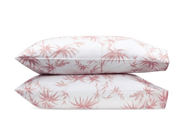 Two stacked pillows from the Matouk Dominique Bedding Collection in Blush with a tropical bamboos design on a white background.
