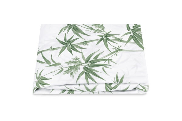 A folded white sheet from the Dominique Bedding Collection, Palm by Matouk, featuring a green leafy botanical pattern on OEKO-TEX Standard 100 certified Egyptian cotton, is displayed against a plain white background.