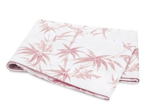 The Dominique Bedding Collection in Blush by Matouk features folded white Egyptian cotton percale with a pink bamboo leaf and floral pattern, and is OEKO-TEX® certified for quality and safety.