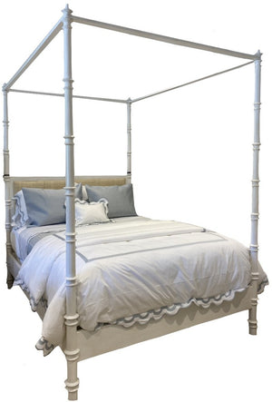 Willa Bed by Oly, featuring a raffia headboard and finished in antique white, styled as a four-poster with canopy frame, dimensions 86D x 66W x 92H, elegantly dressed in blue and white bedding with decorative pillows against a plain background.