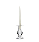 A white taper candle sits in a Simon Pearce Hartland Small Candlestick, expertly handmade by skilled glassblowers, against a plain white background.