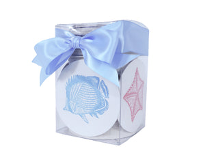 Sealife Coasters by Haute Papier: a clear box of round, letterpressed coasters featuring blue fish and pink seashells, tied with a light blue ribbon—an ideal hostess gift.