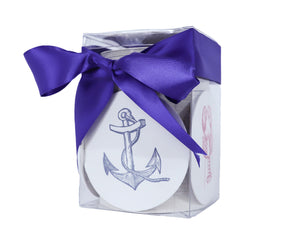 Haute Papier’s Coastal Coasters come in a clear box featuring a navy blue anchor design and are tied with a purple ribbon—an elegant hostess gift.