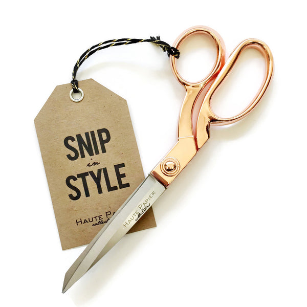 A pair of Haute Papier rose gold handled scissors with a tag that says snip style, made of stainless steel.