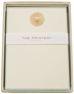 The Printery Sunburst Card Set includes cream-colored ecru cards with a gold sunburst emblem, packaged in a branded box and finished with a paper band.