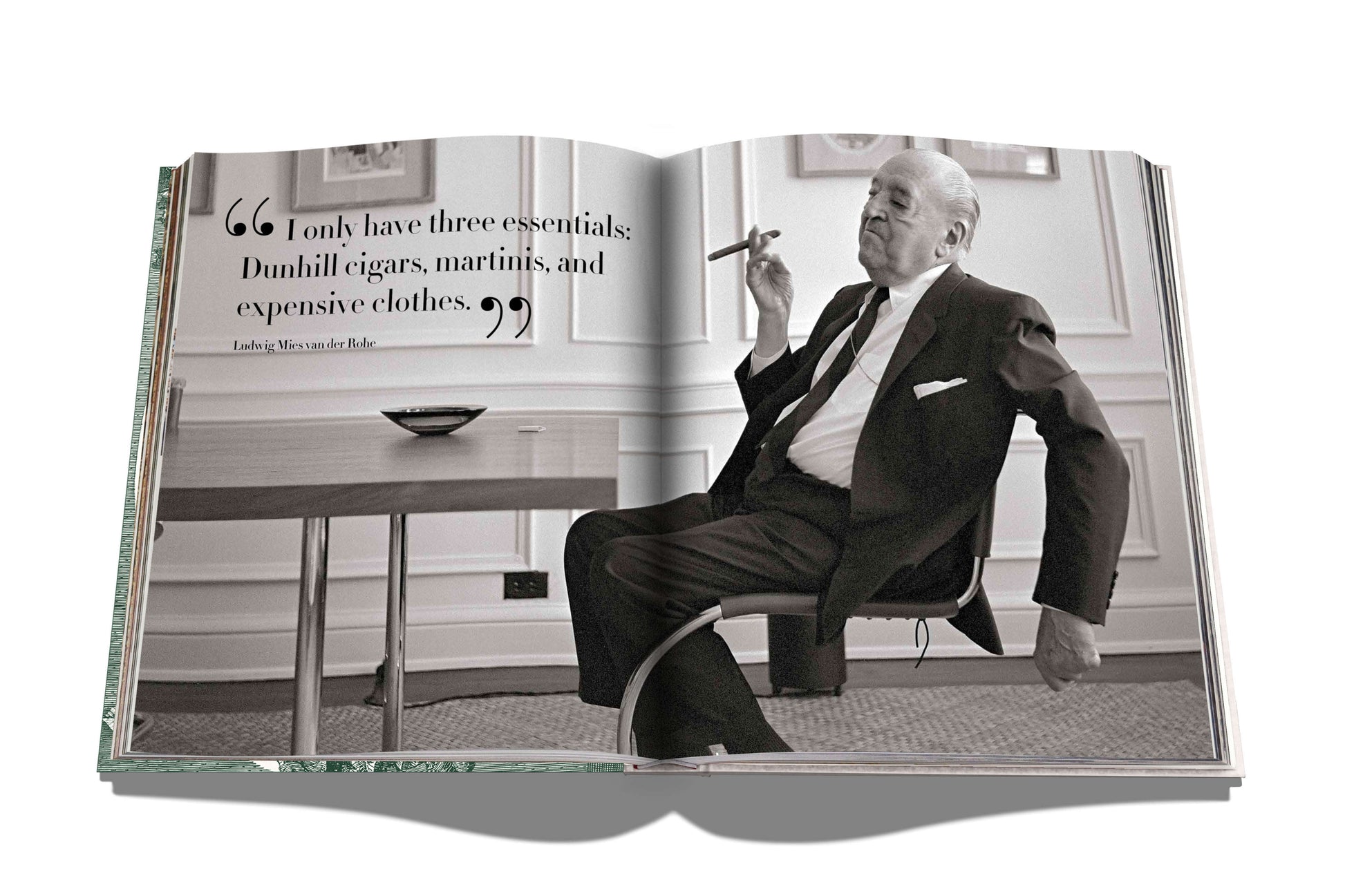 An elegant open book displays a black and white photo of a man in a suit with a cigar, featuring "The Impossible Collection of Cigars" by Assouline. The page highlights essentials like Dunhill cigars, martinis, and luxury clothing—an homage to the finest cigars crafted by renowned makers.
