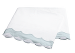 A folded white bedsheet from the Matouk Lorelei Bedding Collection in Pool, featuring a light blue 600 thread count percale scallop applique trim, displayed on a plain background.
