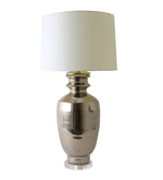 The Marathon Platinum Lustre Lamp by Paul Schneider Ceramics features a reflective solid brass base and a white cylindrical lampshade, shown against a plain white background.