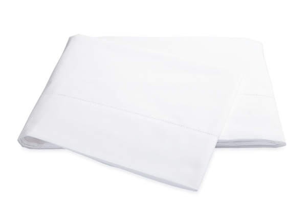 A pair of neatly folded white Matouk Milano Bedding Collection pillowcases isolated on a black background.