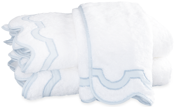 A stack of folded white Matouk Mirasol Bath Collection - Blue cotton terry towels with blue trim.