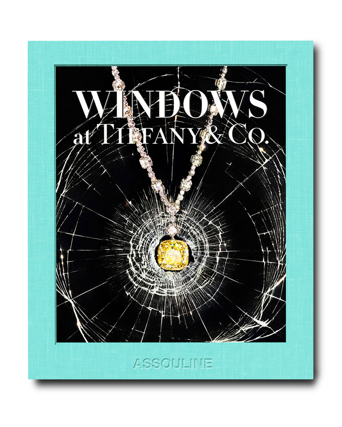 The book cover, "Windows at Tiffany and Co." by Assouline, features a backdrop of shattered glass and highlights a yellow gemstone necklace, evoking Gene Moore's iconic Tiffany & Co. window displays.