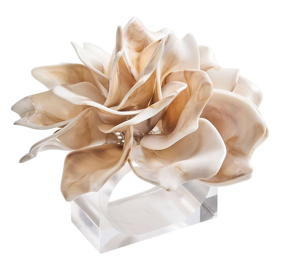 The Kim Seybert Dahlia Ivory Napkin Ring features beige and cream acrylic petals in an abstract layered design, mounted on a clear rectangular base, shown against a white background.