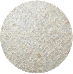 The Camellia Gray Placemat by Kim Seybert features a scalloped round design, crafted from hand-dyed Capiz shells arranged in an iridescent mosaic pattern reminiscent of delicate fish scales.