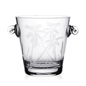 The Palmyra Ice Bucket by William Yeoward Crystal features etched palm trees and round side handles, handmade from clear crystal—perfect for entertaining. Shown against a white background.