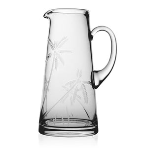 The Palmyra Pitcher by William Yeoward Crystal features a handle and etched palm trees, shown against a white background—a stylish addition to any table setting.