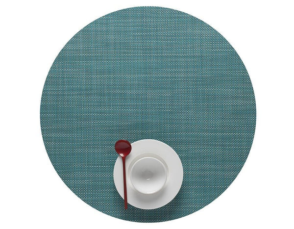 A Round Placemat, Turquoise from Chilewich with a red spoon on it, perfect for any dining occasion.