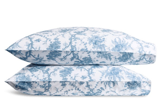 Two stacked pillows with a white background and blue floral pattern from the San Cristobal Bedding Collection, Sky by Matouk, crafted from Luca Egyptian cotton percale and OEKO-TEX® Standard 100 certified.