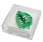 The Tara Wilson Designs Lucite Cocktail Napkin Holder with Monstera Leaf Weight includes white napkins and a decorative green acrylic monstera leaf, making it a stylish and fun hostess gift.
