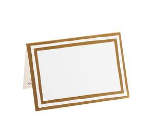 The Caspari Border Stripe Gold Place Cards, crafted from quality cardstock with double gold borders, stand elegantly on a white surface—perfect for stylish tabletop décor.