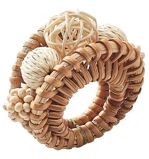 The Playa Napkin Ring by Kim Seybert is a circular hand-woven rattan accessory with natural textured balls, sticks, and organic bead baubles, designed to add a playful touch to your table setting.