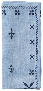 The Kim Seybert Fez Periwinkle Napkin Set features folded light blue linen napkins with navy geometric embroidery and a zigzag stitched border.