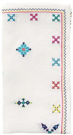 The Fez White/Multi Napkin Set by Kim Seybert features white linen napkins with colorful embroidered geometric and floral designs inspired by Moroccan embroidery on the edges and corners.