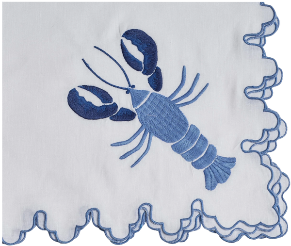 A folded Haute Home July Lobster Napkin, Blue with a scalloped edge and a blue embroidered lobster design.