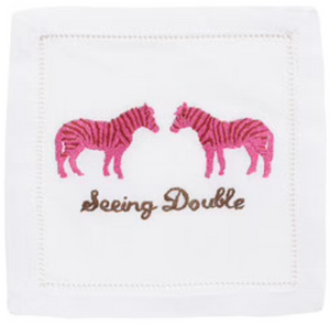 August Morgan Seeing Double Cocktail Napkins feature elegant white linen with classic hemstitching, showcasing two pink zebras facing each other above “Seeing Double” embroidered in brown.