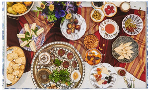 A table set with various dishes, such as sandwiches, scones, fruit, and nuts, elegantly adorned with a floral centerpiece and the Juliska Together at the Table tea service by Juliska, beautifully celebrates life's moments.