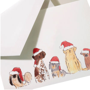 The Crane Santa Dogs Card Set features five cheerful pups in red hats on a holiday note card, partially pulled from a white envelope—perfect for festive greetings.