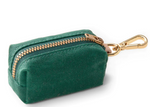 The Foggy Dog Dog Waste Bag Dispenser is a small green fabric pouch with a gold zipper and clasp, designed for eco-friendly poop bags and easy attachment to any leash clip.