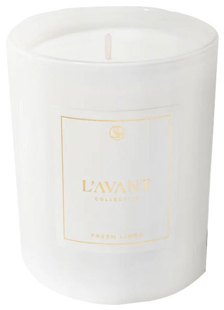 The Fresh Linen Candle by L’Avant Collective is a white soy and coconut blend candle in a glass container, labeled with gold text.