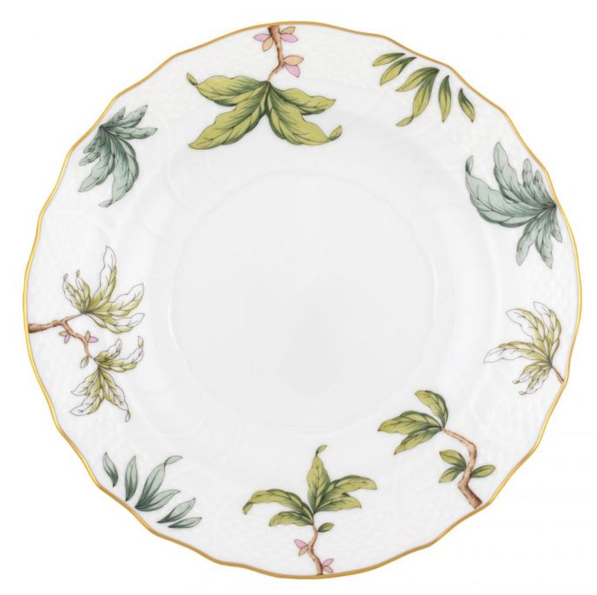 The Herend Foret Garland Collection features a white porcelain plate with a scalloped edge, gold trim, and hand-painted green leaves with pink accents, highlighting the brand's classic artistry.